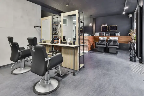 Moderner Friseursalon mit Schneidestühlen, Spiegeln und zwei Waschplätzen.