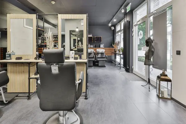 Moderner Friseursalon mit Spiegeln, Schneidestuhl und zwei Waschplätzen.