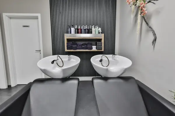 Zwei Waschbecken im Friseursalon mit Shampoos, Handtüchern und Stühlen