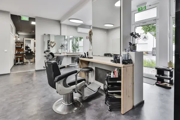Moderner Friseursalon mit Barberstuhl, Spiegeln und Stylingstation am Fenster