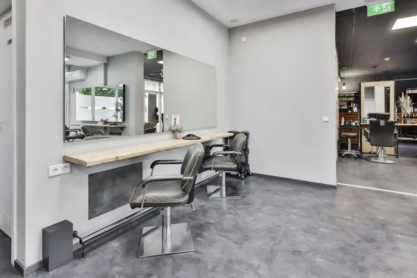 Moderner Friseursalon mit Spiegelwand, zwei Stylingstühlen und Arbeitsablage