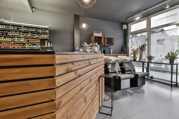 Moderner Friseursalon mit Holztheke, Waschplätzen und Produktregal am Fenster