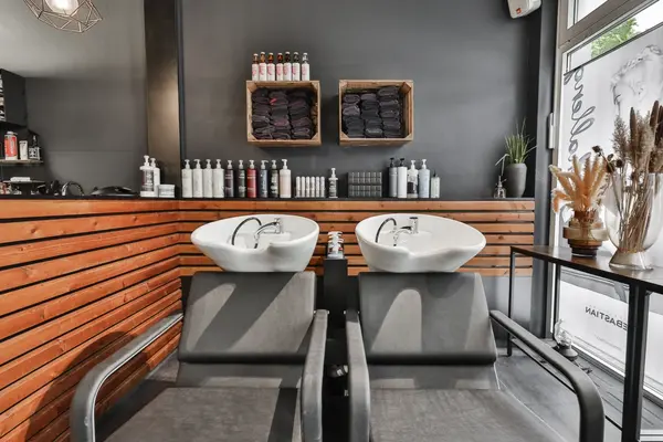 Zwei Waschplätze im Friseursalon mit Shampoobecken, Pflegeprodukten und Handtüchern